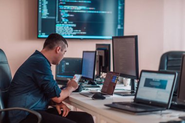 Bir programcı ofisinde otururken akıllı telefon uygulamalarını özenle test ediyor. Yüksek kalite fotoğraf