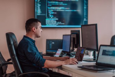 Bir programcı ofisinde otururken akıllı telefon uygulamalarını özenle test ediyor. Yüksek kalite fotoğraf