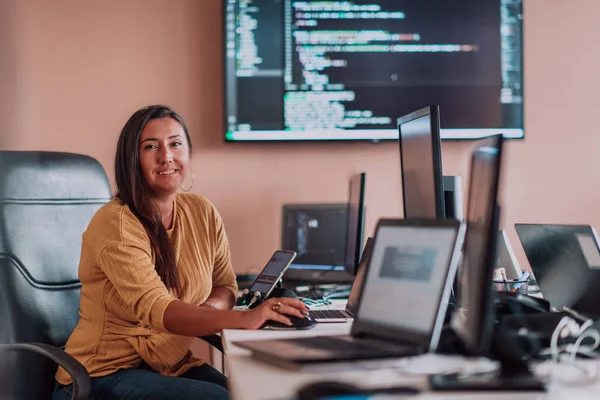 Bilgisayarlarla çevrili bir programcı ofisinde oturan bir iş kadını uzmanlığını ve teknolojiye olan bağlılığını gösteriyor.