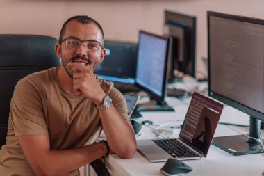 Bir programcı ofisinde otururken akıllı telefon uygulamalarını özenle test ediyor. Yüksek kalite fotoğraf