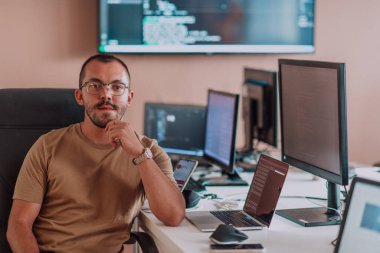 Bir programcı ofisinde otururken akıllı telefon uygulamalarını özenle test ediyor. Yüksek kalite fotoğraf