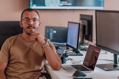 Bir programcı ofisinde otururken akıllı telefon uygulamalarını özenle test ediyor. Yüksek kalite fotoğraf