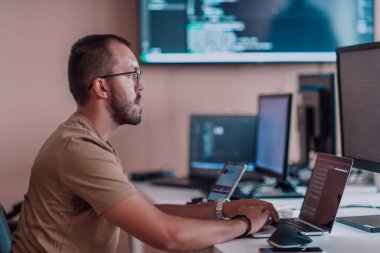 Bir programcı ofisinde otururken akıllı telefon uygulamalarını özenle test ediyor. Yüksek kalite fotoğraf