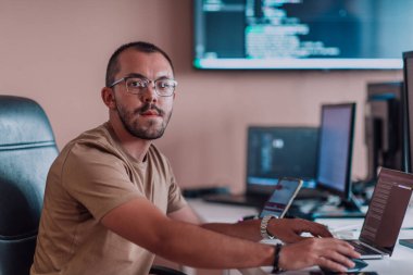 Bir programcı ofisinde otururken akıllı telefon uygulamalarını özenle test ediyor. Yüksek kalite fotoğraf