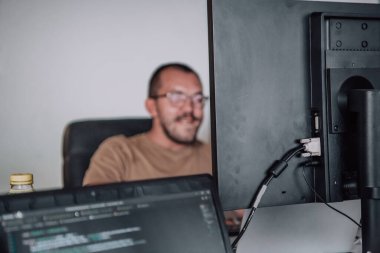 Bir programcı ofisinde otururken akıllı telefon uygulamalarını özenle test ediyor. Yüksek kalite fotoğraf