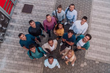 Bir grup iş adamı ve meslektaşının bir arada durduğu, kameraya bakan, birlik ve takım çalışmasını sembolize eden bir fotoğraf.