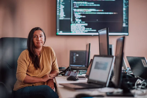 コンピュータに囲まれたプログラマー事務所に座っているビジネスマンは 彼女の専門知識と技術への献身を示しています — ストック写真