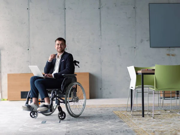 一个坐在轮椅上的残疾商人在现代化的办公室里使用笔记本电脑 高质量的照片 — 图库照片