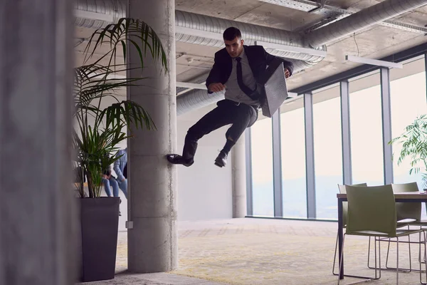 在现代的办公室里 一个拿着公文包的商人在表演令人兴奋的空中杂技 勇敢地跳着反抗重力 以令人叹为观止的敏捷表现出他的敏捷 这一切都令每个人着迷 — 图库照片