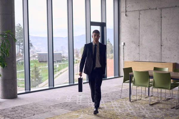 A confident businessman with a briefcase strides through a modern office, exuding charisma and determination, symbolizing success and professional excellence