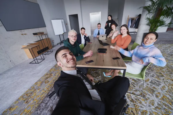 現代のオフィスでは ビジネスマンのグループが会議中にテーブルの周りに集まり 自撮りをしているときの仲間意識とチームワークをキャプチャします — ストック写真