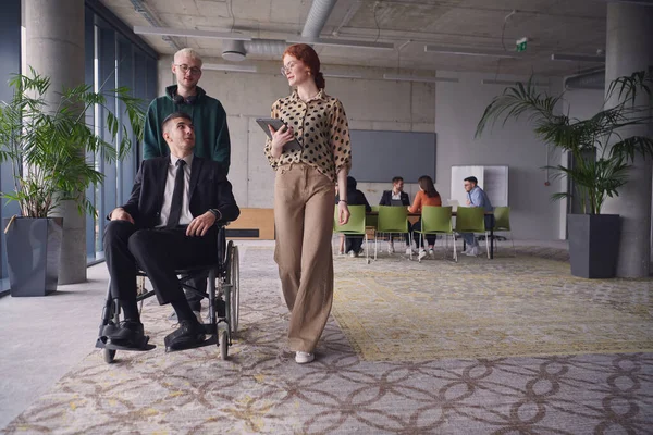 現代のオフィスにいるビジネス 同僚のグループは 車椅子でビジネス フレンドを思いやりを持って操作し チームワークとエンパワーメントを披露することで 包括性とサポートを実証しています — ストック写真