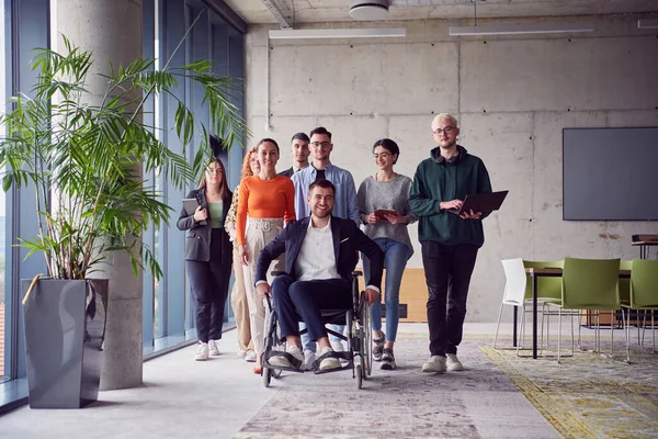 現代的で広々としたオフィスを通して自信を持って一緒に歩み コラボレーション 包括性 団結力を象徴する 車椅子のビジネスマンを含む多様なビジネスマンのグループ — ストック写真