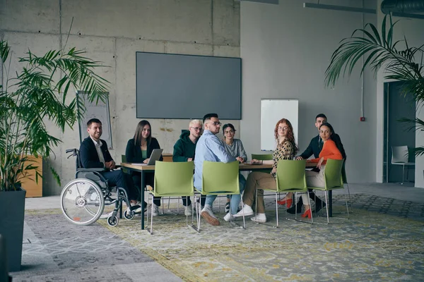 包括一名残疾人在内的各类商业专业人员聚集在一个现代化的办公室 参加一个富有成效的包容性会议 — 图库照片