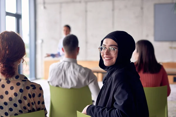 A young hijab woman entrepreneur is attentively listening to a presentation by her colleagues, reflecting the spirit of creativity, collaboration, problem-solving, entrepreneurship, and empowerment