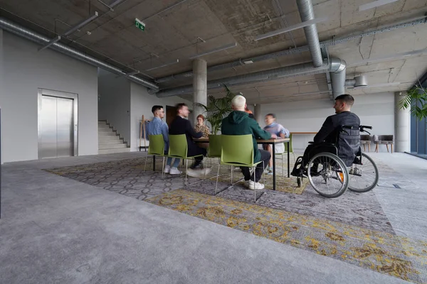 包括一名残疾人在内的各类商业专业人员聚集在一个现代化的办公室 参加一个富有成效的包容性会议 — 图库照片