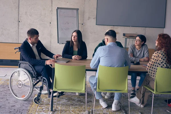 生産的で包括的な会議のための近代的なオフィスに集まった障害者を含む多様なビジネス専門家のグループ — ストック写真