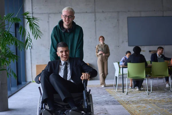 一位年轻的企业家和他的同事是残疾人 他们一起在一个大的 现代的办公室里玩乐 展示了团队精神 包容性和决心的力量 — 图库照片