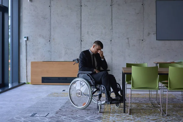 現代的なオフィスの窓から眺める悲しい表情の車椅子に座っている憂うつなビジネスマンは 孤独感を伝えています — ストック写真