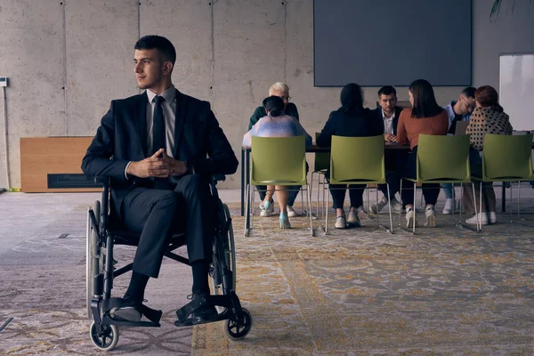 車椅子のビジネスマンは ダイナミックな現代のオフィス環境の中での回復力と成功を象徴する注目を指揮します — ストック写真