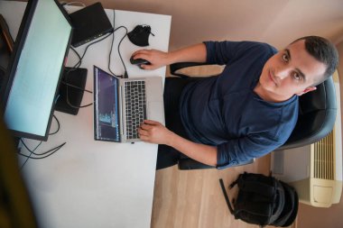 Akıllı telefon uygulamalarını ofisinde otururken özenle test eden programcının üst görünümü