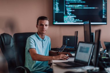 Bir programcı ofisinde otururken akıllı telefon uygulamalarını özenle test ediyor. Yüksek kalite fotoğraf