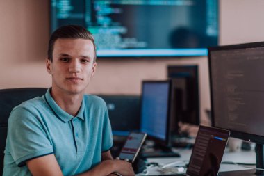 Bir programcı ofisinde otururken akıllı telefon uygulamalarını özenle test ediyor. Yüksek kalite fotoğraf