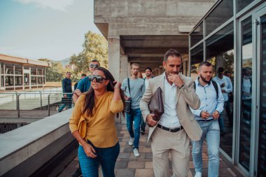 Çeşitli iş adamları ve meslektaşları iş yerlerinin yanından birlikte yürüyorlar, şirkette işbirliği ve takım çalışması sergiliyorlar.