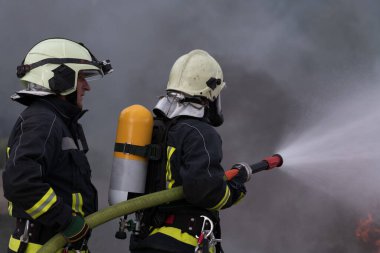 İtfaiyeciler su sisi tipi yangın söndürücü kullanarak yangını kontrol etmek için yangın söndürücü kullanıyorlar, yayılmak için değil. İtfaiyeci endüstriyel ve kamu güvenliği kavramı. Yüksek kalite fotoğraf