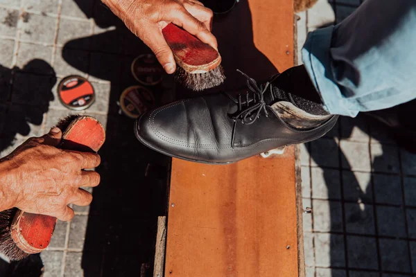 一个老人在街上给一只黑鞋子上光和油漆 — 图库照片