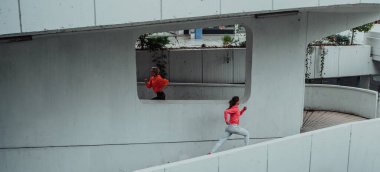 Two women in sports clothes running in a modern urban environment. The concept of a sporty and healthy lifestyle. 