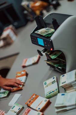 Banka çalışanları banka kasasında kağıt banknotları sıralarken ve sayarken para sayma makinesi kullanıyorlar. Bankada büyük miktarda para var.. 