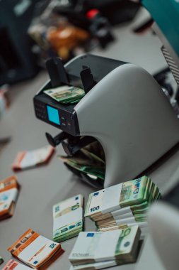 Banka çalışanları banka kasasında kağıt banknotları sıralarken ve sayarken para sayma makinesi kullanıyorlar. Bankada büyük miktarda para var.. 