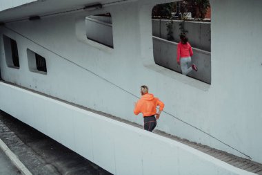 Modern bir şehir ortamında koşan spor elbiseli iki kadın. Sportif ve sağlıklı yaşam tarzı kavramı. 