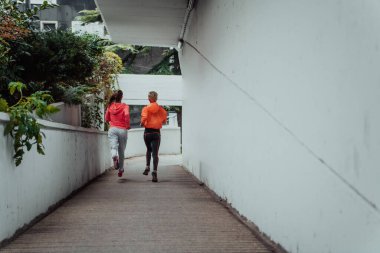 Two women in sports clothes running in a modern urban environment. The concept of a sporty and healthy lifestyle. 