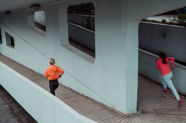 Modern bir şehir ortamında koşan spor elbiseli iki kadın. Sportif ve sağlıklı yaşam tarzı kavramı. 