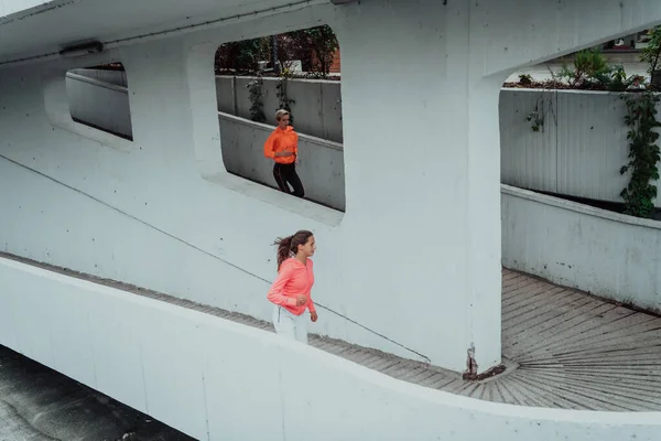 Δύο Γυναίκες Αθλητικά Ρούχα Τρέχουν Ένα Σύγχρονο Αστικό Περιβάλλον Έννοια — Φωτογραφία Αρχείου