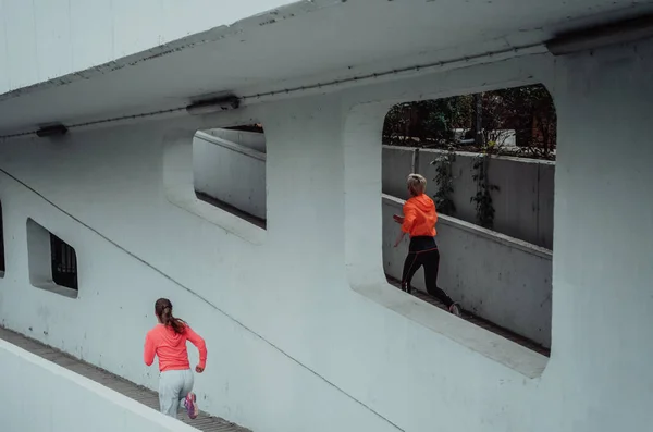 两名身穿运动服的妇女在现代城市环境中跑步 运动和健康生活方式的概念 — 图库照片
