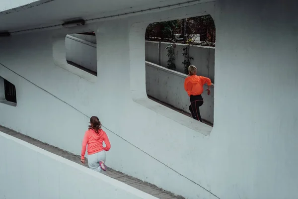 两名身穿运动服的妇女在现代城市环境中跑步 运动和健康生活方式的概念 — 图库照片