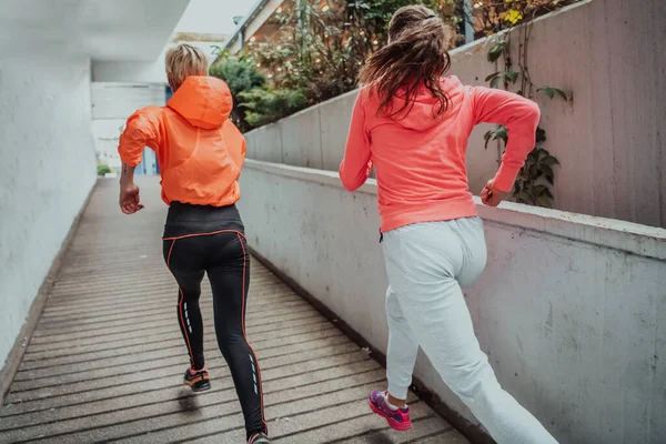 Two women in sports clothes running in a modern urban environment. The concept of a sporty and healthy lifestyle.