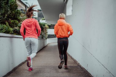 Two women in sports clothes running in a modern urban environment. The concept of a sporty and healthy lifestyle. 