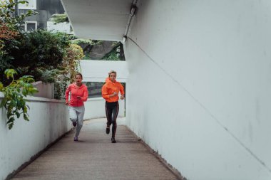 Modern bir şehir ortamında koşan spor elbiseli iki kadın. Sportif ve sağlıklı yaşam tarzı kavramı. 