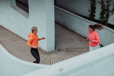 Two women in sports clothes running in a modern urban environment. The concept of a sporty and healthy lifestyle. 