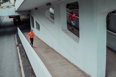 Modern bir şehir ortamında koşan spor elbiseli iki kadın. Sportif ve sağlıklı yaşam tarzı kavramı. 