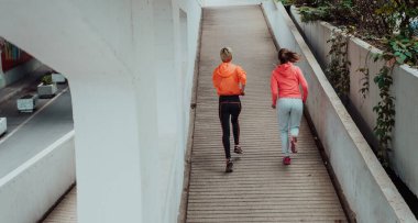 Two women in sports clothes running in a modern urban environment. The concept of a sporty and healthy lifestyle. 
