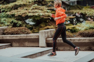  Spor kıyafetli bir sarışın şehirde şehir içinde koşuşturuyor. Seksi sarışının sağlıklı bir yaşam tarzı var.