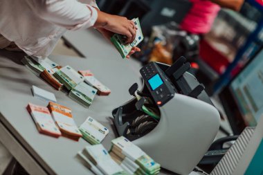 Banka çalışanları banka kasasında kağıt banknotları sıralarken ve sayarken para sayma makinesi kullanıyorlar. Bankada büyük miktarda para var.. 