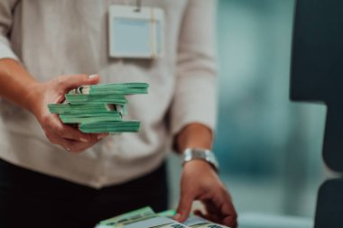 Banka çalışanları banka kasasında kağıt banknotları sıralarken ve sayarken para sayma makinesi kullanıyorlar. Bankada büyük miktarda para var.. 