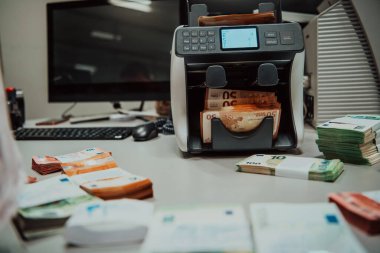 Banka çalışanları banka kasasında kağıt banknotları sıralarken ve sayarken para sayma makinesi kullanıyorlar. Bankada büyük miktarda para var.. 