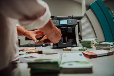 Banka çalışanları banka kasasında kağıt banknotları sıralarken ve sayarken para sayma makinesi kullanıyorlar. Bankada büyük miktarda para var.. 